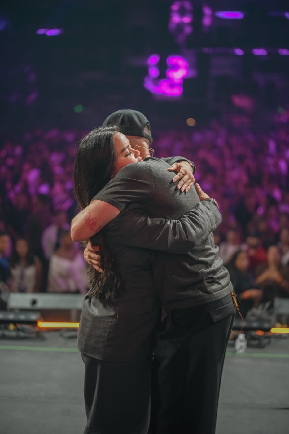 Valentina y Javi abrazados en el escenario, con el público detrás
