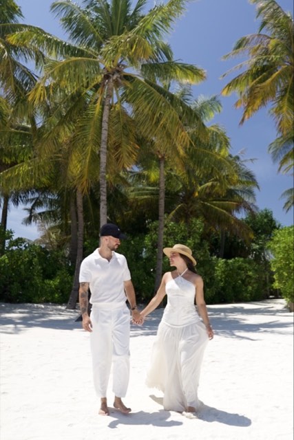 Valentina y Javi paseando de la mano por una playa blanca